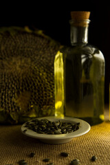 Sunflower, sunflower seeds, sunflower oil, oil production, glass bottle of sunflower oil is on the table, village, wooden background, baggy tablecloth