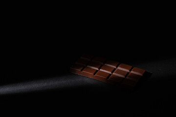 Chocolate bar illuminated with a soft point light, on a black background