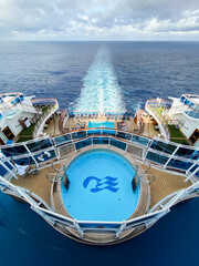 Emerald Princess Cruise ship. Aft (rear) of ship with pools on the Sports Deck and Rivera Deck. Princess Cruises Logo with wave pattern and sea witch face. Ship's wake.  - obrazy, fototapety, plakaty