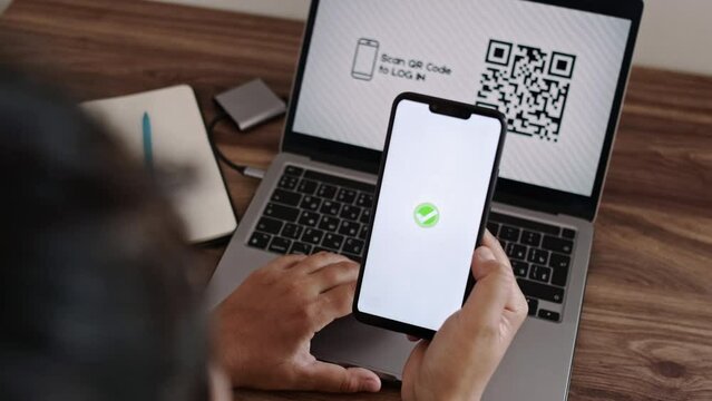 Log In Web Page Using Smartphone with QR Code Scanning Application. Verification or Autentification with Bar Code Reader. Synchronously Successful Approval on Laptop and Mobile Phone. CloseUp View