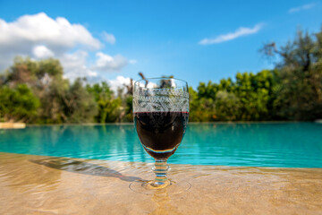 czerwone wino w delikatnym kieliszku na skraju basenu