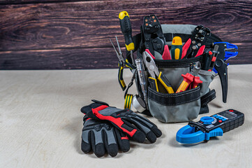 Electrician's bag with a professional electric tools, gloves, multimeter.