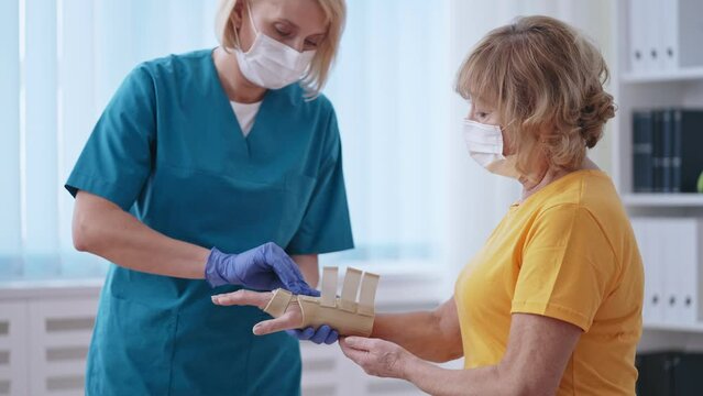Female orthopedist fixing cast to patient's hand, bone fracture treatment 