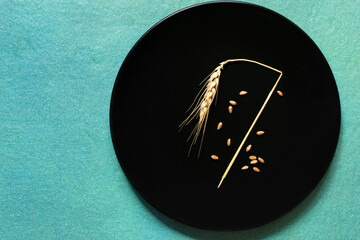Broken ear of wheat and some grains on black plate