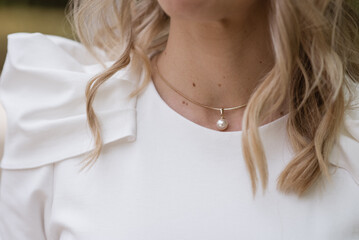 Wedding. Jewels. The bride in a white dress putting a necklace around her neck