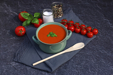 Tomatensuppe mit frischen Tomaten, Basilikum und Gewürzen auf einem dunklem Hintergrund.