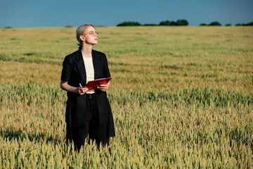 employee of an agricultural firm with notebook checks the quality of wheat in the field