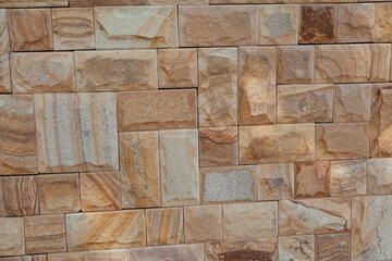 Wall of laid yellow natural stone..