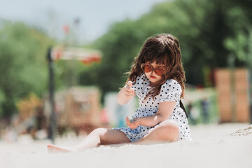Naklejka premium beautiful little girl in white dress playing on beach