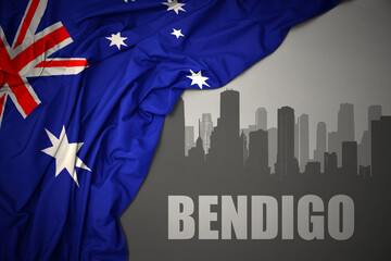 abstract silhouette of the city with text Bendigo near waving national flag of australia on a gray background.