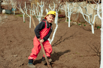  child helps in the garden.a little boy is digging the ground. the boy digs into the garden.