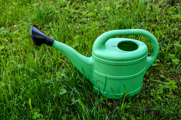 Green plastic sprinkling can outdoor in garden. Watering can.