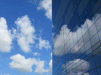blue sky with clouds and a glass building reflecting them