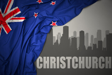 abstract silhouette of the city with text Christchurch near waving national flag of new zealand on a gray background.