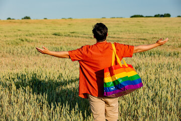 Man with rainbow bag on wheat field