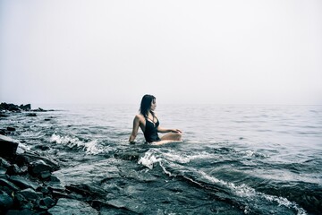Girl in a black swimsuit in the sea during cloudy weather