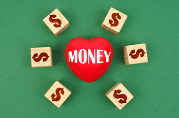 On a green surface, a heart with the inscription - money and cubes with a dollar symbol