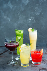 Five summer refreshing cocktails with lemon and mint, vegan beverages on dark marble textured table, heathy lifestyle
