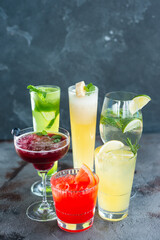Six summer refreshing cocktails with lemon and mint, vegan beverages on dark marble textured table, heathy lifestyle
