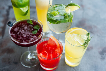 Fototapeta na wymiar Six summer refreshing cocktails with lemon and mint, vegan beverages on dark marble textured table, heathy lifestyle, flat lay