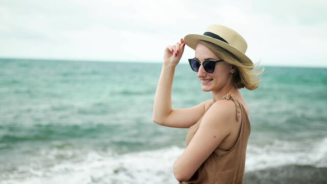 Happy girl in hat and glasses on ocean background