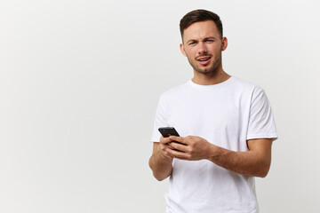 Shocked confused tanned handsome man in basic t-shirt get fake message from frauds posing isolated on over white studio background. Copy space Banner Mockup. Distance online communication concept