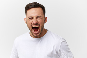 Aggressive evil tanned handsome man in basic t-shirt scream at camera posing isolated on over white studio background. Copy space Banner Mockup. People emotions. Domestic violence concept