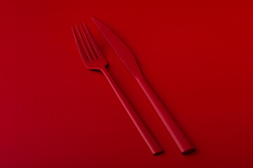 Red cutlery on the red background.