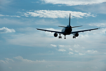 Passenger airplane landing against blue cloudy sky