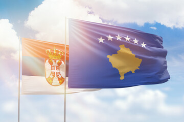 Sunny blue sky and flags of kosovo and serbia