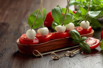 Mozzarella with basil and tomatoes on an old wooden table.