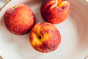 three ripe peaches in white bowl
