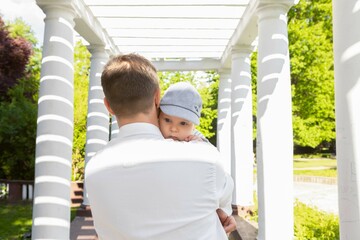 Obraz premium Baby in the arms of dad on a sunny day on a light background