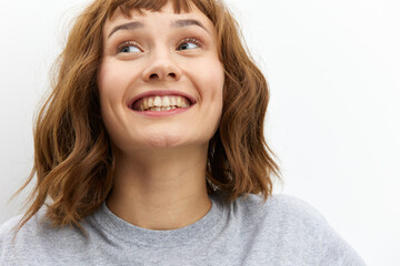 a happy, very joyful woman stands on a white background in a gray T-shirt smiling broadly expressing her emotions. Close horizontal photo