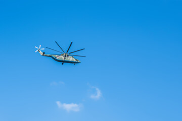A military helicopter is flying against the blue sky