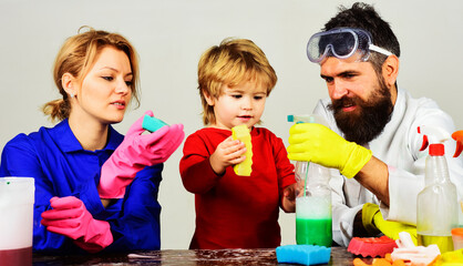 Family cleans together. Mother and father teach little son clean up with cleaning spray and sponge.