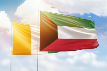 Sunny blue sky and flags of kuwait and ivory coast