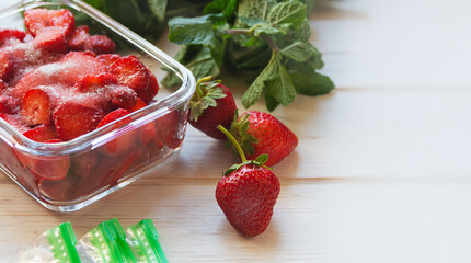 Preparing berries for freezing. Red ripe freshly picked strawberries and packages for freezing on a white table.