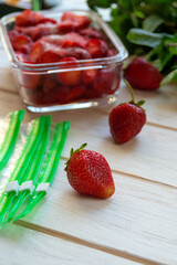 Preparing berries for freezing. Red ripe freshly picked strawberries and packages for freezing on a white table.
