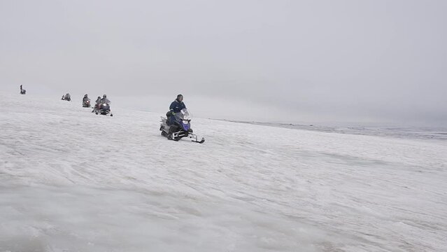 Group of tourists riding snowmobiles with a guide at Vatnajokull glacier in Iceland. Active sport, recreation, lifestyle.