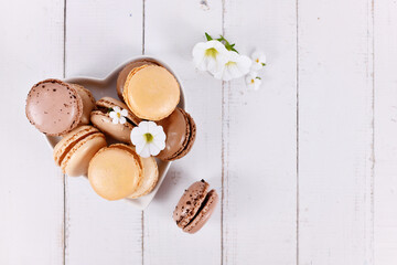 Natural brown, beige and cream colored French macarons on heart shaped plate with copy space