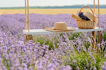 lavender field, hat and picnic basket on a swing swing, a symbol of summer vacation