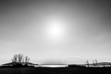 Shore of Trasimeno lake Umbria, Italy with big, clear sky and sun in the middle