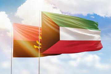 Sunny blue sky and flags of kuwait and angola