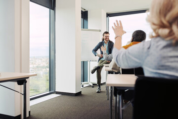 Seniors are sitting in the classroom, rising hands and asking questions about lesson their educator.