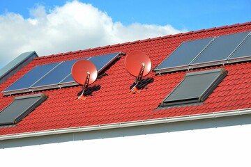 Solaranlage, Satelliten-Antenne und Dachfenster auf einem Ziegeldach montiert