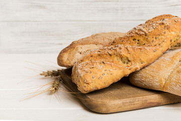 Freshly baked bread on cutting board against white wooden background. perspective view bread with copy space