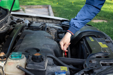 Fototapeta na wymiar checking car engine oil level under hood with dipstick 