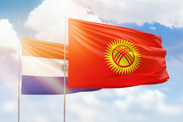 Sunny blue sky and flags of kyrgyzstan and paraguay