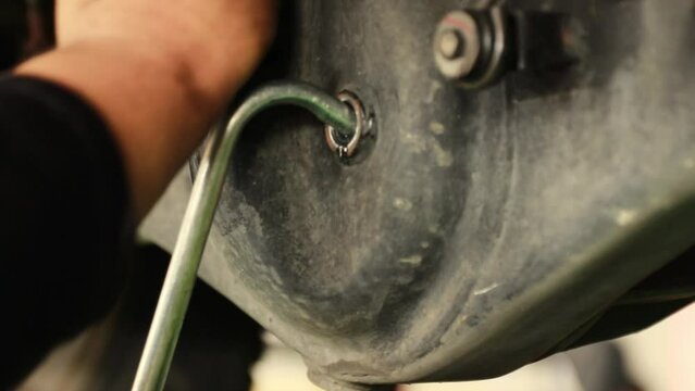 Male technician at a car service center checks the condition of the pickup truck's new rear differential gear oil to full level and installs the cover bolts to ensure safety and tidiness.